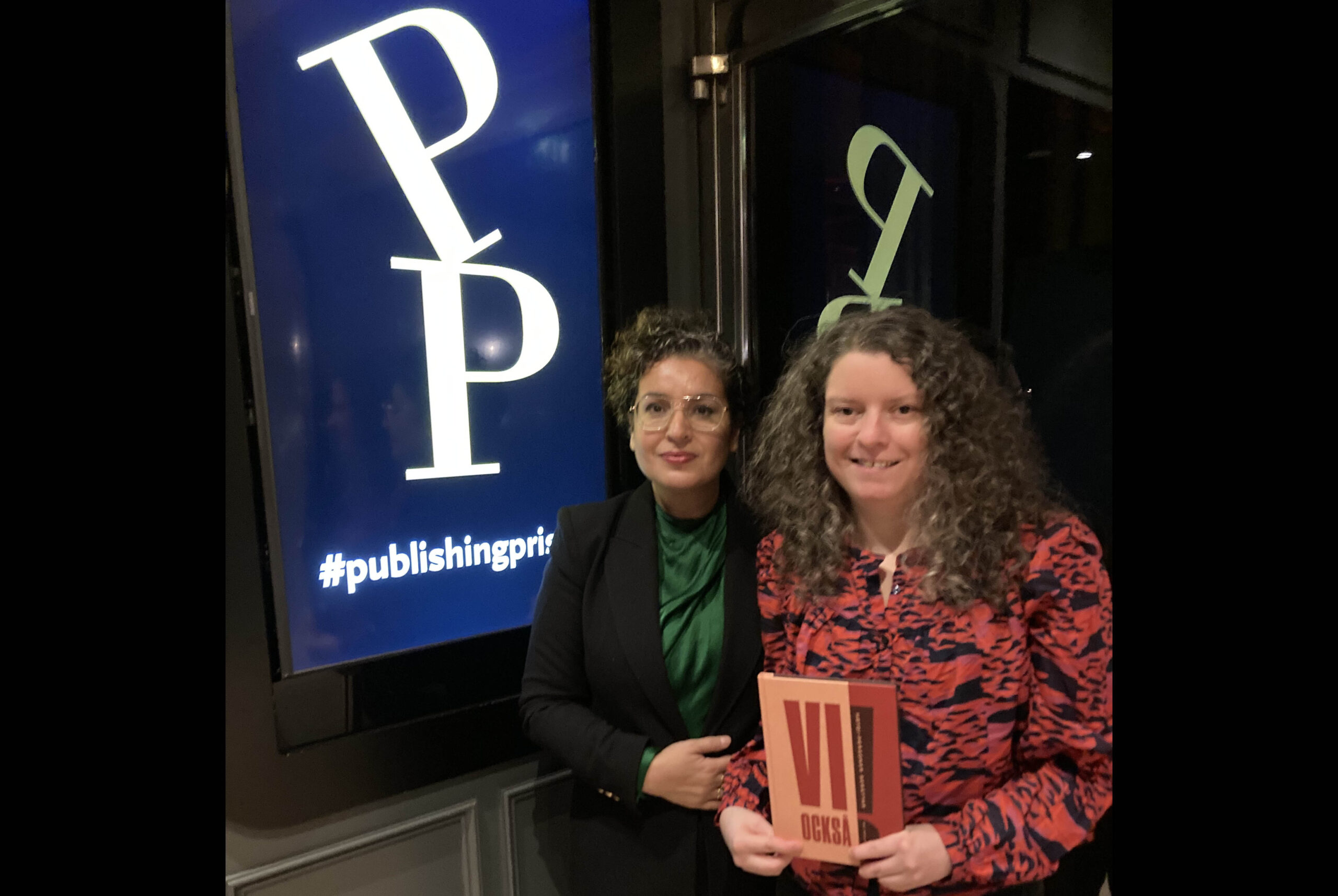 RFSL:s Trifa Shakely och redaktör Maria Niemi håller upp boken "Vi också" framför Publishingpriset-loggan